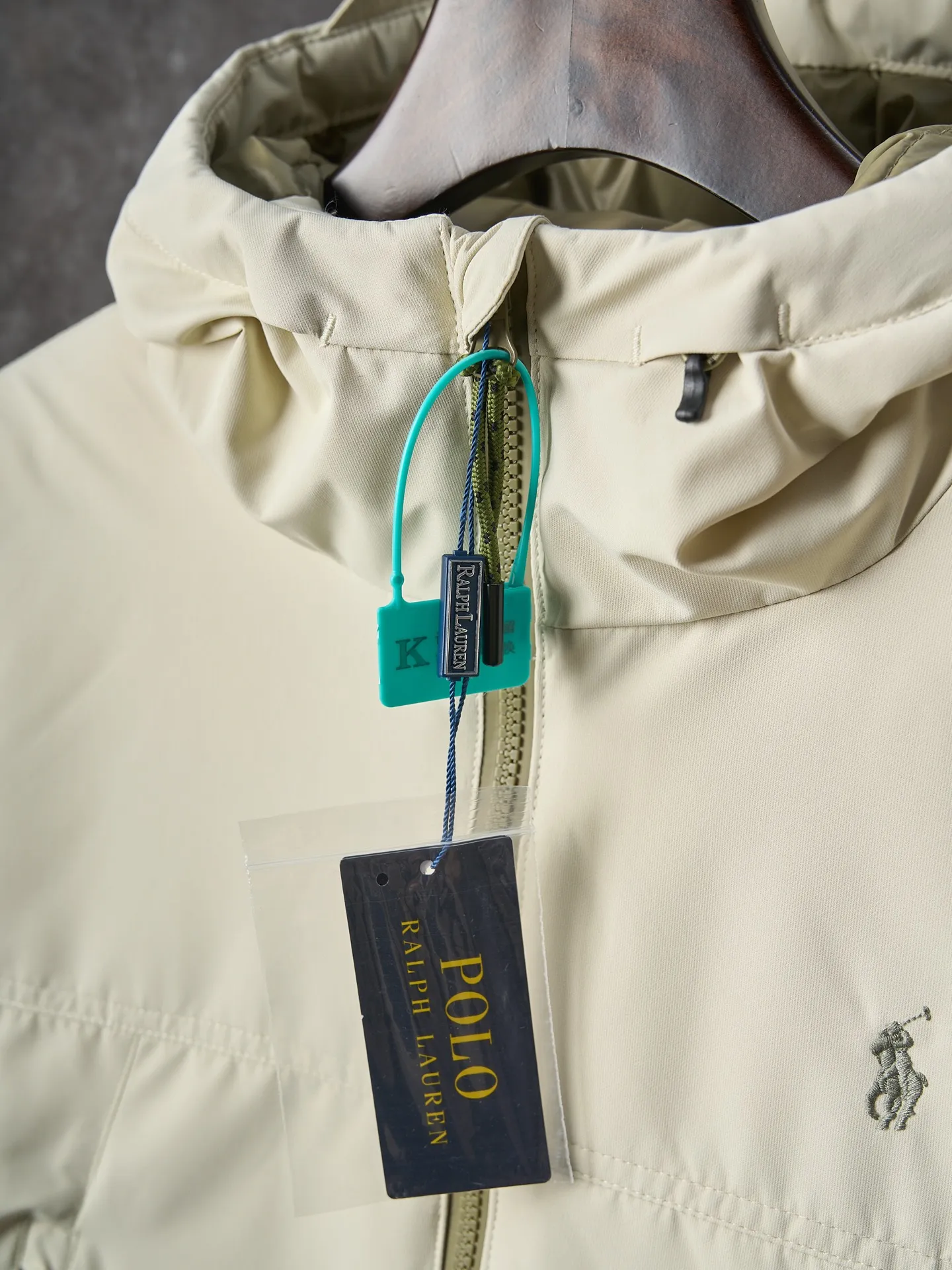 P980 Actual auction】Ralph Lauren/Ralph Lauren pony embroidered zipper hooded down jacket [Ready stock] S M L XL high-quality filling: 90 white duck down is selected, weighing 220g, ensuring excellent thermal insulation performance. After strict screening and processing, the velvet is not easy to be drilled, ensuring durability. The density of high-density nylon taffeta is about 210T-300T, with a smooth and slightly matte surface, excellent windproof and waterproof properties (with DWR water-repellent treatment), strong wrinkle resistance and easy care, in line with the positioning of American casual "durable and practical".  The inner lining is made of 100% polyamide. The high-density and tight weaving process prevents fine lint from getting out of the gaps in the fabric. The smooth surface improves the putting on and taking off experience, and the excellent wear and tear resistance ensures damage caused by frequent use, while the light and soft texture does not affect the overall weight.  The classic jacket has a slightly loose fit, slightly dropped shoulder line (shoulder width is 1-2cm wider than the standard fit), is hip-length, and has slightly tapered straight sleeves, taking into account both freedom of movement and casual style.  The adjustable Velcro on the cuffs allows you to freely adjust the tightness according to the thickness of your wrist and personal preferences, effectively preventing cold wind from intruding, and improving the warmth performance.  In terms of storage, the two front zipper pockets are convenient for you to place frequently used items, and the zipper design ensures that items are not easily lost. A built-in pocket on the left side of the chest provides a safe storage space for some small private items.  The drawstring design at the hem allows you to adjust the shape of the jacket according to your body shape and dressing needs. Whether it is loose and casual or slim and neat, you can easily control it.  Embroidery technology: Polo horse logo on the left chest: flat satin stitch embroidery (satin embroidery), embroidery thread: 100% polyester high color fastness embroidery thread (the color number is consistent with the brand’s standard red color card), stitch density 12-15 stitches/cm, the outline of the horse logo is clear, and the details of the rider and horse are burr-free.  Embroidery positioning: precise positioning through the template (12cm from the neckline and 8cm from the placket) to ensure left and right symmetry and centering.